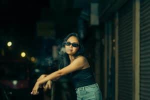 Woman in Sunglasses Vaping on Street